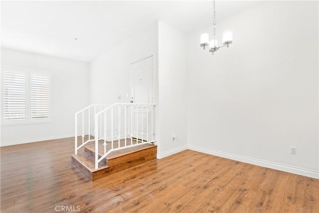 spare room featuring wood-type flooring and a notable chandelier