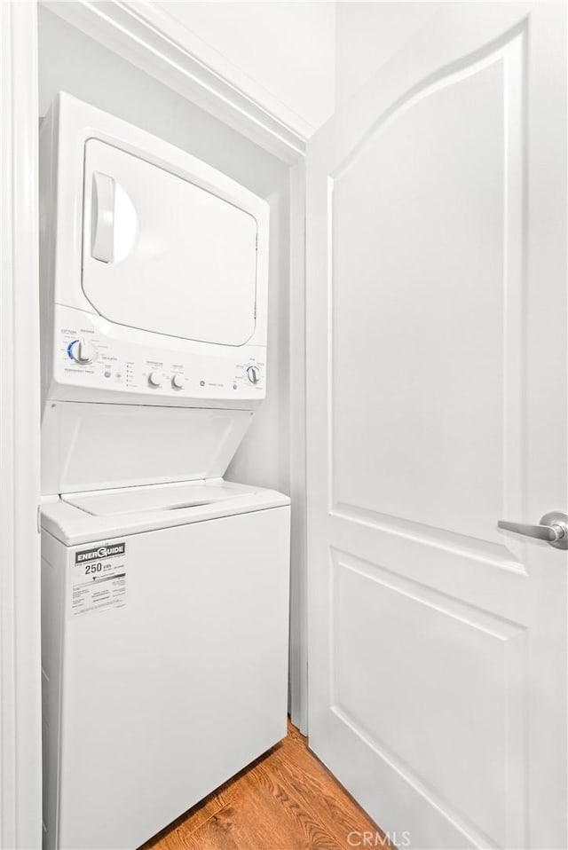 clothes washing area featuring stacked washer / dryer and hardwood / wood-style floors