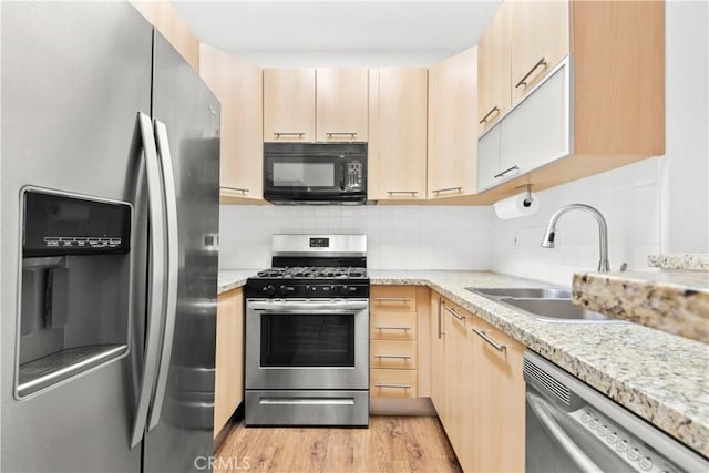 kitchen with appliances with stainless steel finishes, light brown cabinetry, sink, and light stone countertops