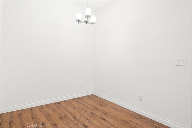 unfurnished room featuring an inviting chandelier and hardwood / wood-style floors