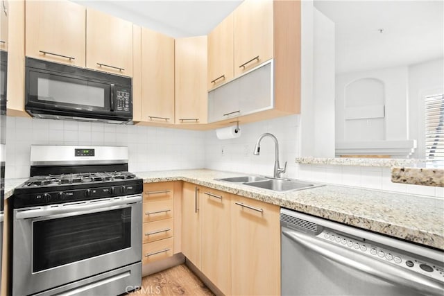 kitchen with sink, light hardwood / wood-style flooring, light brown cabinets, appliances with stainless steel finishes, and decorative backsplash