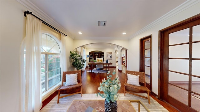 living area with plenty of natural light, wood-type flooring, and crown molding