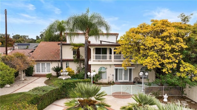 rear view of property with a balcony and french doors