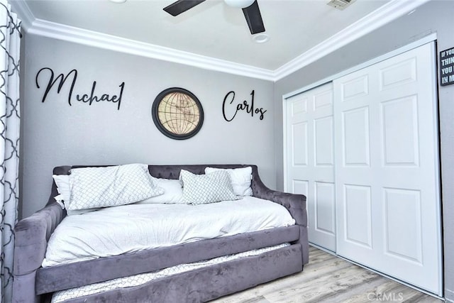 bedroom with a closet, hardwood / wood-style flooring, ceiling fan, and ornamental molding