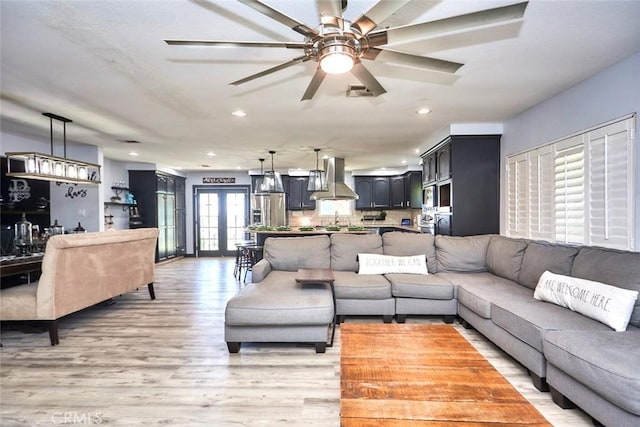 living room featuring french doors, light wood-type flooring, and ceiling fan