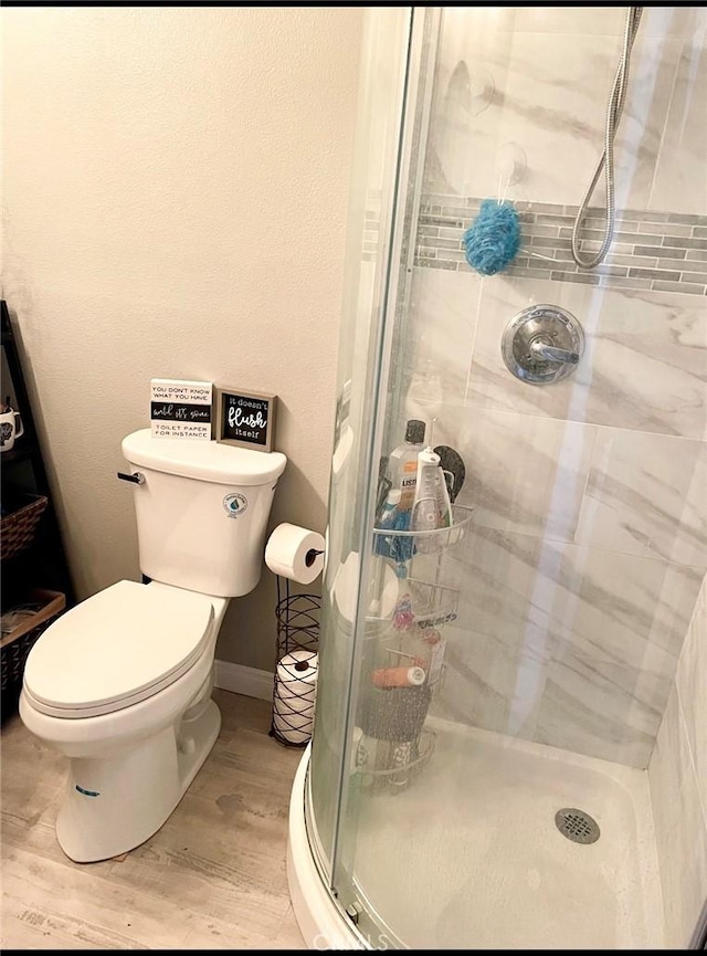 bathroom featuring walk in shower, hardwood / wood-style floors, and toilet