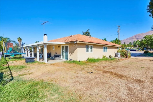 back of property featuring a patio area, a mountain view, and a trampoline