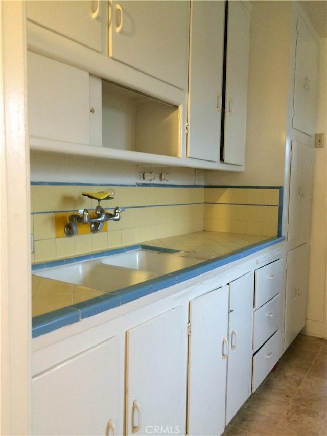 bathroom with backsplash, tile patterned floors, and sink