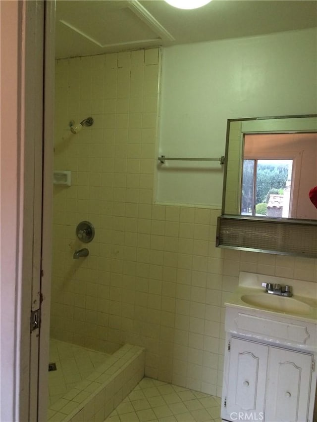 bathroom featuring tile patterned flooring, vanity, and tiled shower