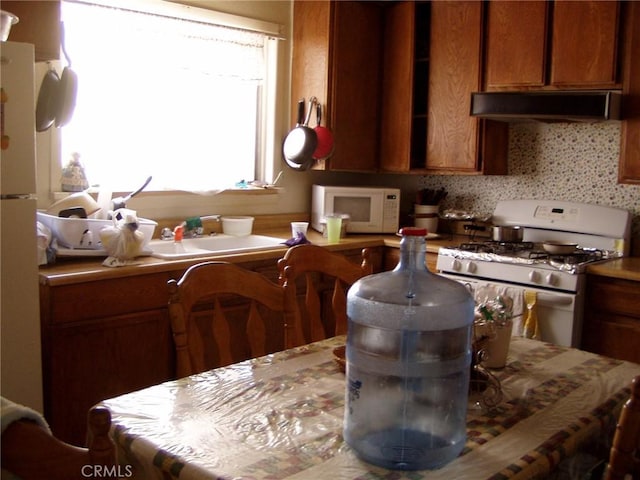 kitchen featuring sink, white appliances, extractor fan, and backsplash