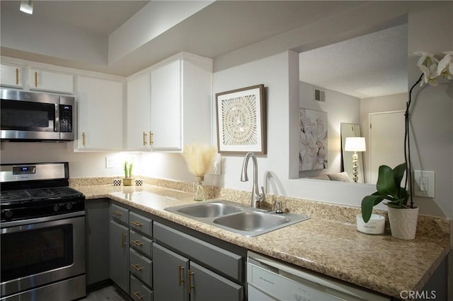 kitchen with gray cabinets, stainless steel appliances, white cabinetry, and sink