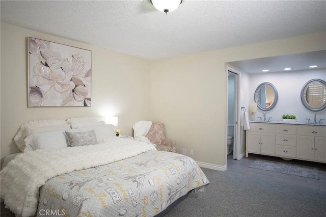 bedroom featuring a textured ceiling, dark carpet, and sink