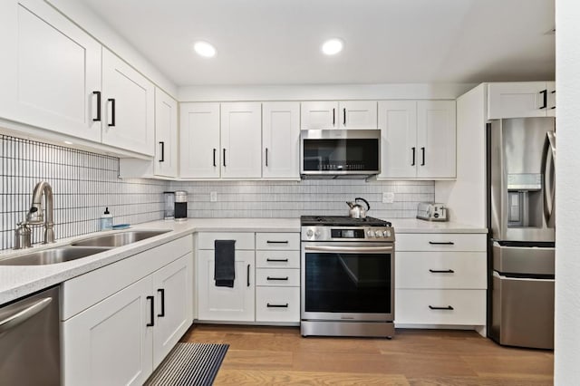 kitchen with white cabinets, stainless steel appliances, and light hardwood / wood-style floors