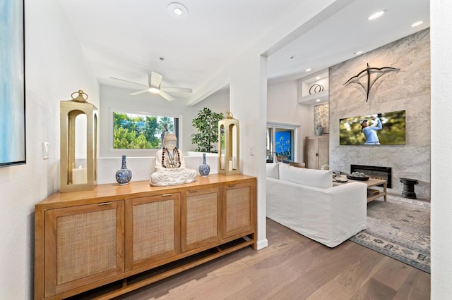 living room with ceiling fan, wood-type flooring, tile walls, and a premium fireplace