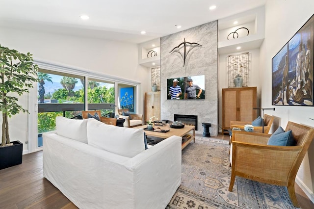 living room with hardwood / wood-style floors, high vaulted ceiling, and a tiled fireplace