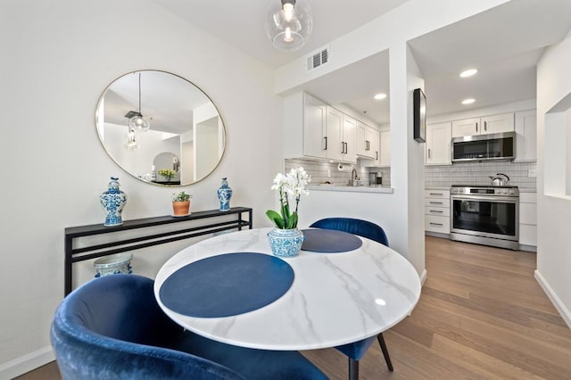 dining area with light wood-type flooring and sink