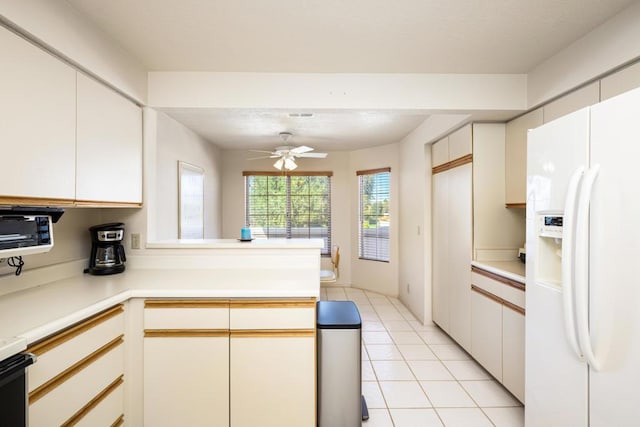 kitchen with white refrigerator with ice dispenser, kitchen peninsula, ceiling fan, light tile patterned floors, and white cabinetry