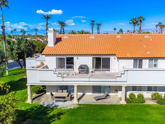 back of house featuring a lawn, a balcony, and a patio