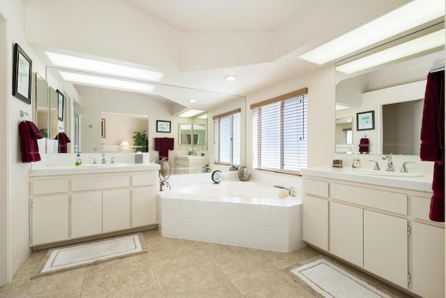 bathroom with tile patterned floors, a relaxing tiled tub, and vanity