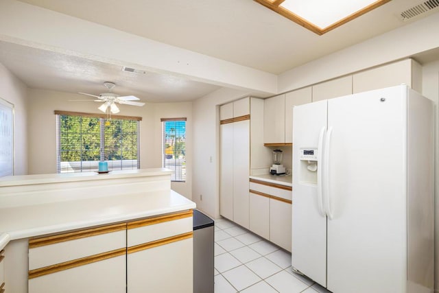 kitchen featuring white cabinets, ceiling fan, light tile patterned flooring, and white refrigerator with ice dispenser