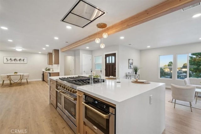 kitchen featuring decorative light fixtures, light hardwood / wood-style floors, beam ceiling, a center island, and appliances with stainless steel finishes