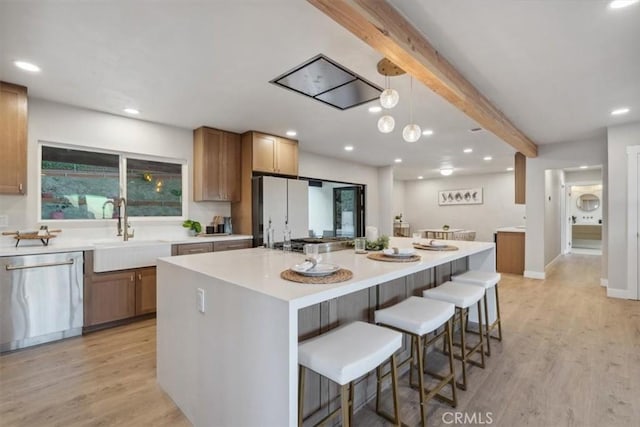 kitchen featuring a kitchen island, stainless steel appliances, light hardwood / wood-style floors, sink, and beam ceiling