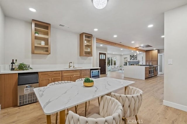 kitchen with light wood-type flooring, a center island, wine cooler, sink, and stainless steel gas range oven