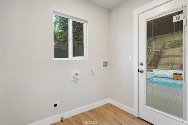 clothes washing area with light hardwood / wood-style floors, hookup for a washing machine, and hookup for an electric dryer