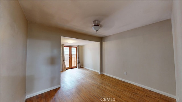 empty room with wood finished floors, ceiling fan, and baseboards