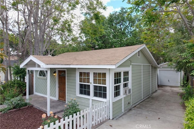 view of front of home with fence, a shingled roof, an outbuilding, a garage, and concrete driveway