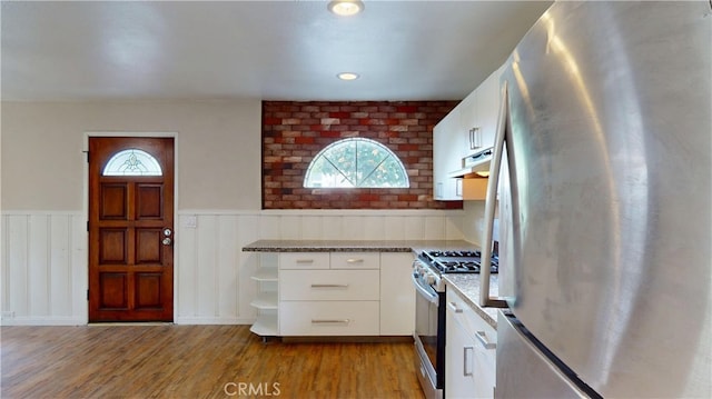kitchen featuring light wood finished floors, range hood, appliances with stainless steel finishes, and a healthy amount of sunlight