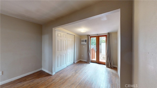 entryway with baseboards, french doors, light wood-style flooring, and a wall mounted AC