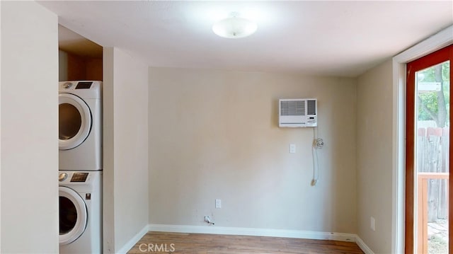 clothes washing area with stacked washer / drying machine, light wood finished floors, heating unit, laundry area, and baseboards