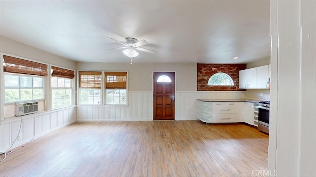 kitchen featuring stainless steel gas stove, ceiling fan, light wood-style flooring, and plenty of natural light
