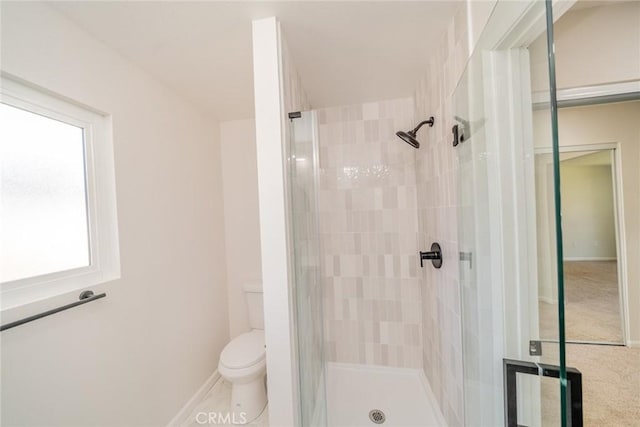 bathroom featuring an enclosed shower, toilet, and a wealth of natural light