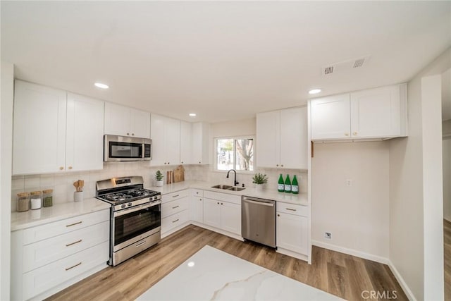 kitchen with light hardwood / wood-style flooring, stainless steel appliances, white cabinetry, and sink