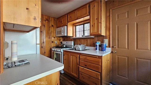 kitchen featuring dark hardwood / wood-style flooring, white appliances, and wood walls