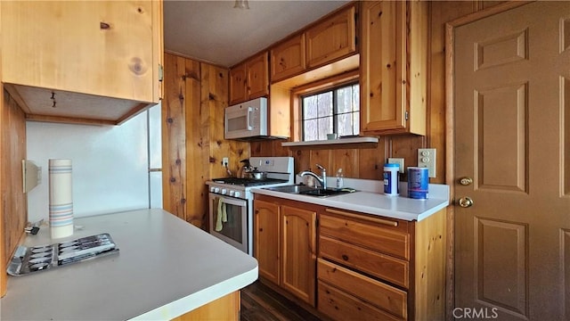 kitchen with white appliances, wooden walls, and sink