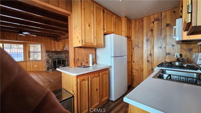 kitchen with ceiling fan, dark wood-type flooring, beamed ceiling, white refrigerator, and wood walls