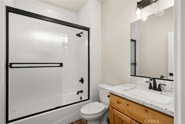 full bathroom featuring vanity, toilet, and shower / bath combination with glass door