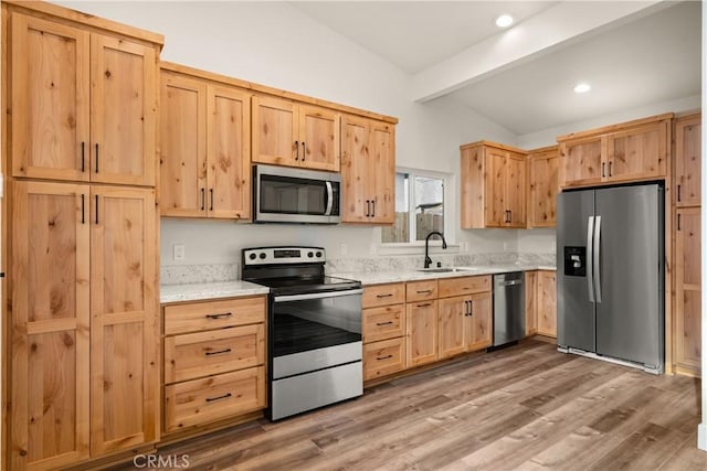 kitchen featuring lofted ceiling with beams, sink, stainless steel appliances, and light hardwood / wood-style flooring