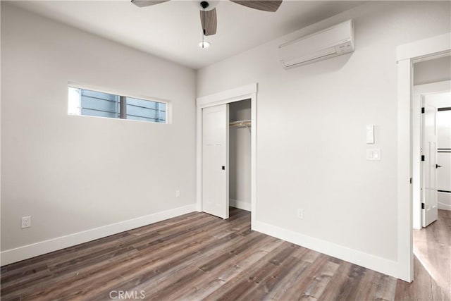 unfurnished bedroom with a wall mounted AC, ceiling fan, a closet, and dark wood-type flooring