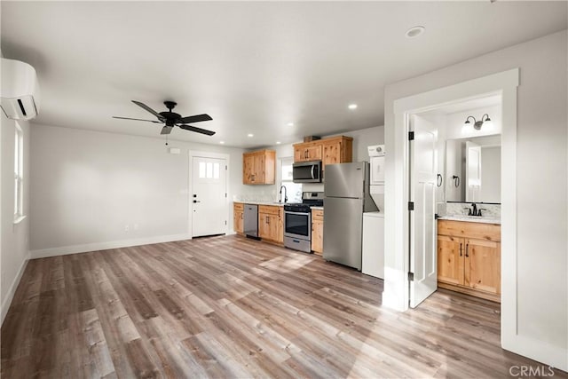 kitchen featuring a wall mounted air conditioner, light hardwood / wood-style floors, sink, and appliances with stainless steel finishes