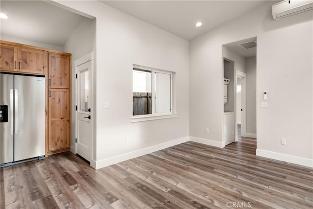 kitchen featuring a wall unit AC, stainless steel fridge, dark wood-type flooring, and vaulted ceiling