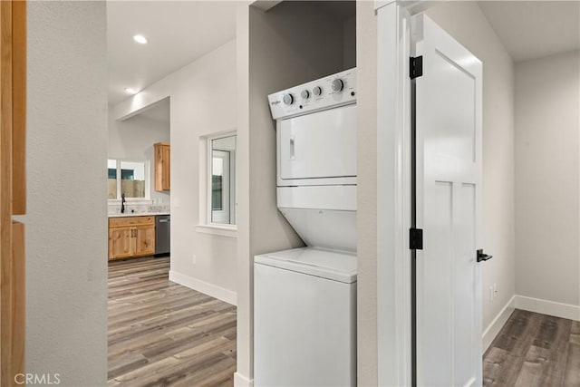 laundry room featuring hardwood / wood-style floors and stacked washer / drying machine