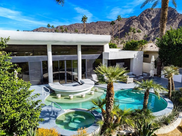 view of swimming pool with a mountain view and an in ground hot tub