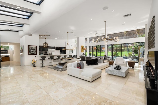 living room featuring a towering ceiling and ceiling fan with notable chandelier