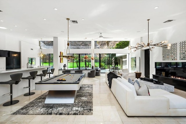 living room with ceiling fan with notable chandelier, light tile patterned flooring, and billiards