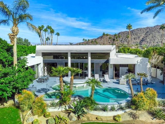 rear view of property featuring a patio area, a mountain view, an outdoor hangout area, and a pool with hot tub