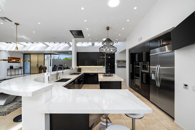 kitchen featuring kitchen peninsula, sink, pendant lighting, a breakfast bar area, and built in fridge